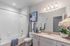 Elegant, bright bathroom with modern fixtures, featuring a sleek vanity, polished stone countertop, and vibrant decorative accents.