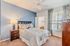 Cozy bedroom with stylish decor, featuring a comfortable bed, modern nightstand, and large window with patterned curtains.
