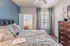Inviting bedroom with modern decor, featuring a cozy bed, patterned cushions, and a view through large windows with elegant curtains.
