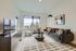 Bright and modern living room featuring a sleek grey sofa, stylish coffee table, and large windows with scenic views.