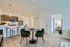 Chic open-concept living space with modern kitchen, stylish bar seating, and elegant dining area featuring green velvet chairs.