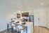 Modern apartment kitchen with a sleek countertop, bar seating, stylish pendant lighting, and stainless steel appliances.