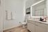 Modern bathroom with ambient lighting, sleek vanity, and stylish decor. Features elegant wood flooring and a spacious layout.