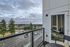 Chic apartment balcony offering serene views of lush trees and a peaceful neighborhood under a cloudy sky.