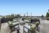 Chic rooftop patio with stylish seating, offering stunning city and mountain views under clear blue skies.