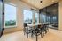 Stylish dining area with modern chairs and a large wooden table, featuring floor-to-ceiling windows offering scenic views of lush greenery.