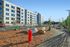 Modern apartment complex with clean architecture, scenic landscaping, and vibrant outdoor space, featuring a prominent red fire hydrant and a winding pathway.