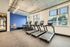 Contemporary fitness center with state-of-the-art treadmills and elliptical machines, featuring large windows for natural light and a vibrant blue accent wall.