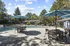 Charming outdoor pool area with inviting patio tables and umbrellas, surrounded by lush greenery and modern residential buildings.