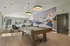 Chic recreation area with a stylish pool table, modern lighting, and vibrant mural in a bright, airy setting.