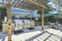 Charming outdoor space with dual stainless steel grills under a rustic pergola, adjacent to a cozy seating area with umbrella, ideal for al fresco dining.