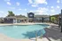 Charming residential pool area with a stylish clubhouse and elegant lounging spaces under a bright blue sky.