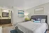 Inviting bedroom with elegant decor, featuring a plush bed, stylish lighting, and a modern bathroom vanity.