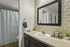 Modern bathroom with elegant design featuring a large mirror, stylish countertop, and chic patterned shower curtain.