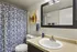 Modern bathroom featuring a chic vanity, vibrant geometric artwork, and a stylish patterned shower curtain.