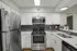 Modern kitchen with sleek stainless steel appliances, elegant white cabinetry, and a stylish black tile backsplash.