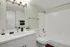 Modern bathroom with sleek white fixtures, large mirror, and elegant lighting, offering a refreshing and sophisticated ambiance.