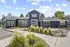 Charming modern blue house with inviting entrance and lush landscaping under a bright blue sky.