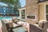 Charming outdoor patio with cozy wicker seating, a modern stone fireplace, and a refreshing swimming pool, perfect for relaxation and entertaining.
