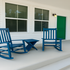 Inviting porch with classic blue rocking chairs and a vibrant green door, perfect for relaxation.