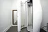 Sleek modern corner featuring a futuristic tanning booth and elegant full-length mirror in a bright, minimalist room.