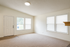 Bright and inviting interior featuring a spacious carpeted room with large windows and a modern entryway.