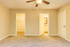 Inviting empty bedroom featuring plush carpeting, a ceiling fan, and access to a bright walk-in closet and bathroom.