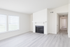 Bright and airy living room with sleek gray flooring, large windows, and a modern white brick fireplace.