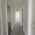 Bright and inviting hallway with soft carpet flooring, leading to multiple rooms and a charming door at the end.