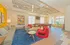 Modern living area featuring chic red chairs, cozy sofas, vibrant artwork, and a pool table under a stylish wooden ceiling.