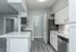 Modern kitchen with sleek white cabinetry, stylish countertops, stainless steel appliances, and elegant gray flooring.