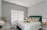 Elegant bedroom with a plush green headboard, soft neutral decor, and abundant natural light from the window.