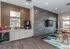 Chic apartment lounge with modern kitchenette, artistic wall textures, and stylish high-top seating.