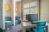 Modern apartment interior featuring a stylish workspace with a sleek desk and ergonomic chair, accented by geometric patterned partition and cozy seating area.