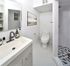 Contemporary bathroom with modern fixtures, sleek white vanity, and stylish patterned tile in shower area.