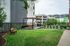 Inviting outdoor space featuring a lush green lawn, cozy wooden benches, and a modern pergola with an elegant dining area.