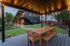 Charming outdoor space with a cozy wooden pergola and dining area overlooking a beautifully landscaped garden.