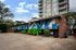 Contemporary urban apartment building featuring vibrant mural artwork and spacious parking area, surrounded by lush greenery.