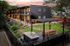 Charming apartment complex with modern design, featuring outdoor dining area, lush garden, and ambient lighting for a cozy evening ambiance.
