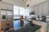 Bright and modern kitchen with high ceilings, featuring a large granite island, stainless steel appliances, and ample natural light from a large window.