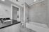 Modern bathroom featuring elegant tiled bathtub and sleek granite countertops, with a convenient in-unit washer-dryer.
