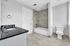 Elegant bathroom with sleek black countertop, modern fixtures, and a chic tiled bathtub for a luxurious experience.