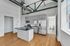 Sleek industrial-style kitchen with open beams, modern stainless steel appliances, and elegant hardwood flooring.