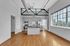 Bright and spacious kitchen with modern stainless steel appliances, elegant cabinetry, industrial-style ceiling accents, and expansive windows showcasing scenic city views.