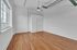 Bright and airy room featuring polished hardwood floors, large window with city view, and modern ceiling fan.