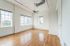Bright and spacious room with elegant hardwood flooring, large windows providing abundant natural light, and modern ceiling fan, ideal for creating a comfortable living space.