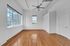 Bright, spacious room with hardwood floors, large windows for ample natural light, and modern ceiling fan.