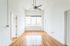 Bright and airy apartment space featuring elegant hardwood floors, large windows, and a ceiling fan, perfect for modern living.