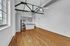 Airy apartment featuring hardwood floors, vaulted ceilings with exposed beams, modern kitchen with stainless steel appliances, and large windows enhancing natural light.