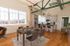 Chic loft apartment with open-concept dining and kitchen area, featuring large windows, modern appliances, and stylish wooden flooring.